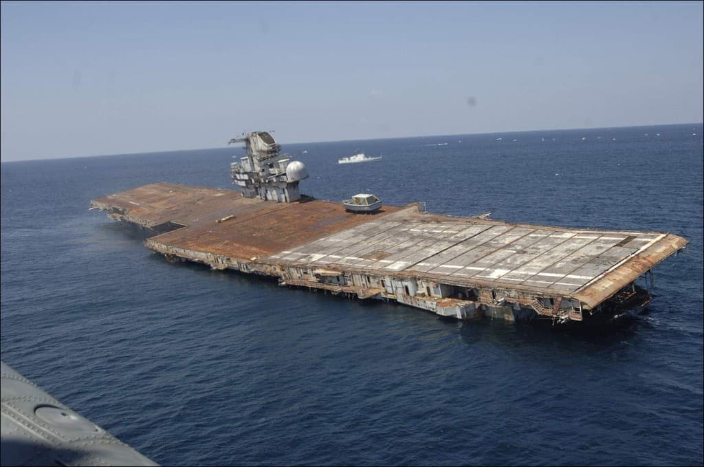 Aerial of USS Oriskany sitting low in calm blue water before scuttling