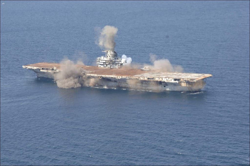 Charges detonating along USS Oriskany as smoke rises from the island
