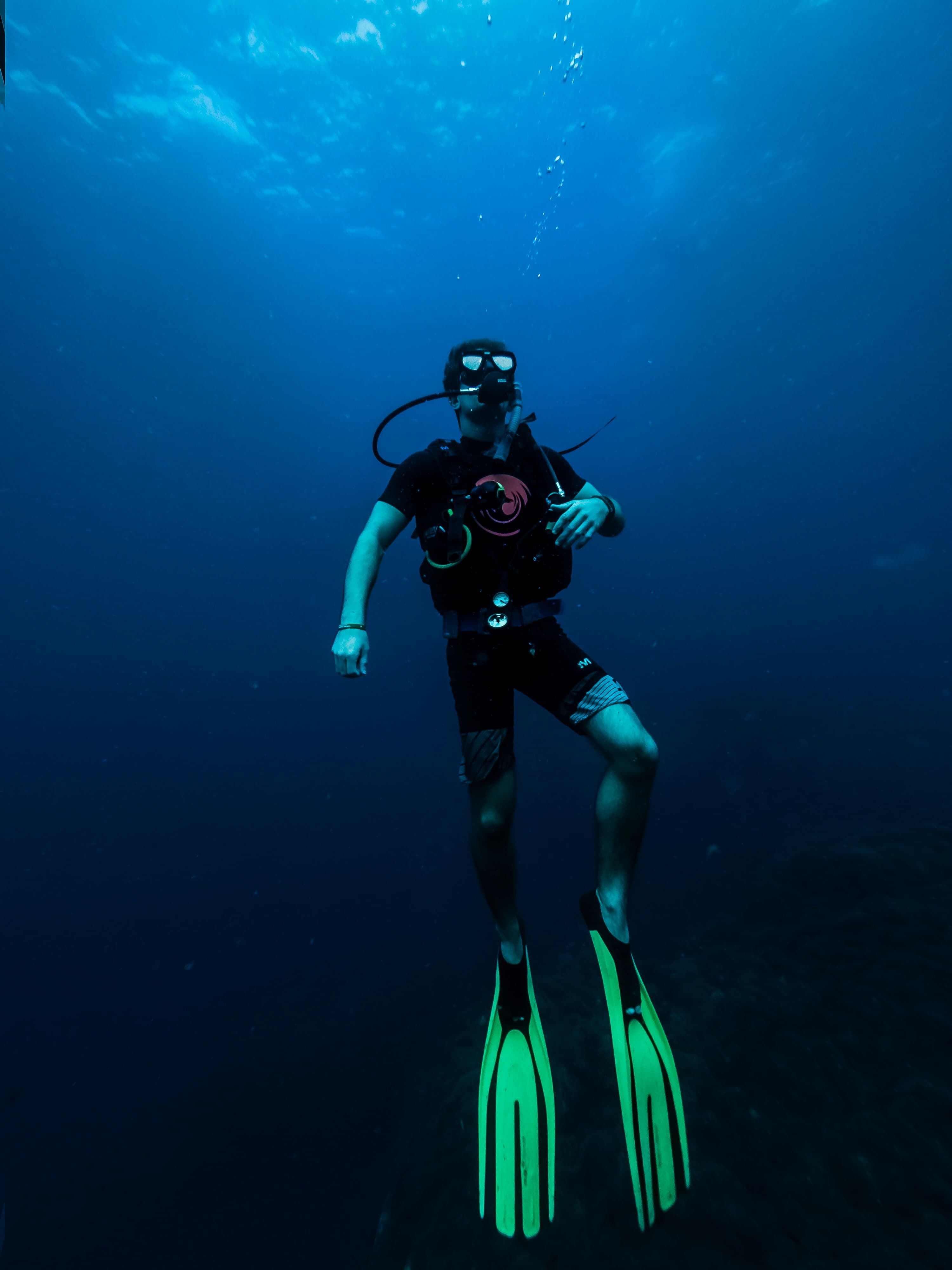 Diver hovering in deep blue water with lime fins